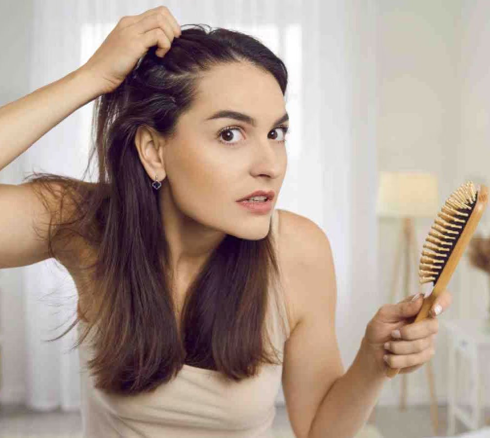woman with hair loss looking in the mirror