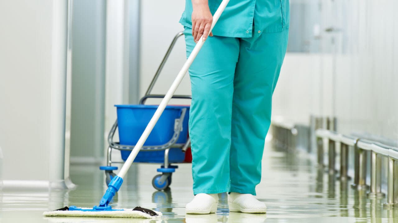 a woman nurse wiping floor with a mop in hairfree hairgrow clinic